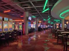 Slot aisle under green ceiling lights at Elements Casino Surrey